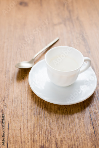 white coffee cup with coffee stains next to spoon and on wooden background