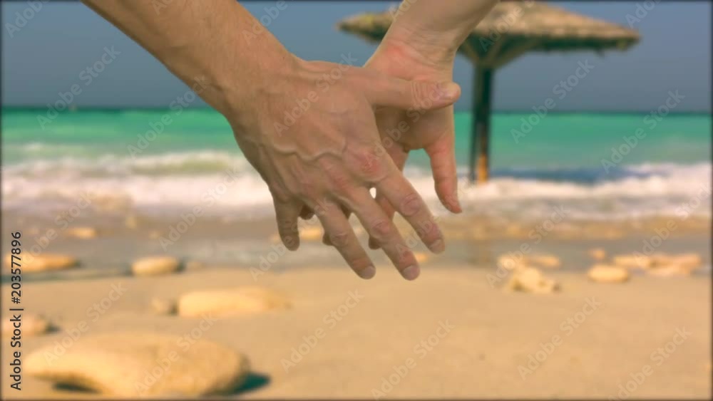 Couple holding hands in lock with tropical resort and ocean on background Couple holding hands in lock with tropical resort and ocean on background