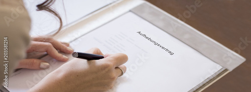 junge Frau unterzeichnet Aufhebungsvertrag 