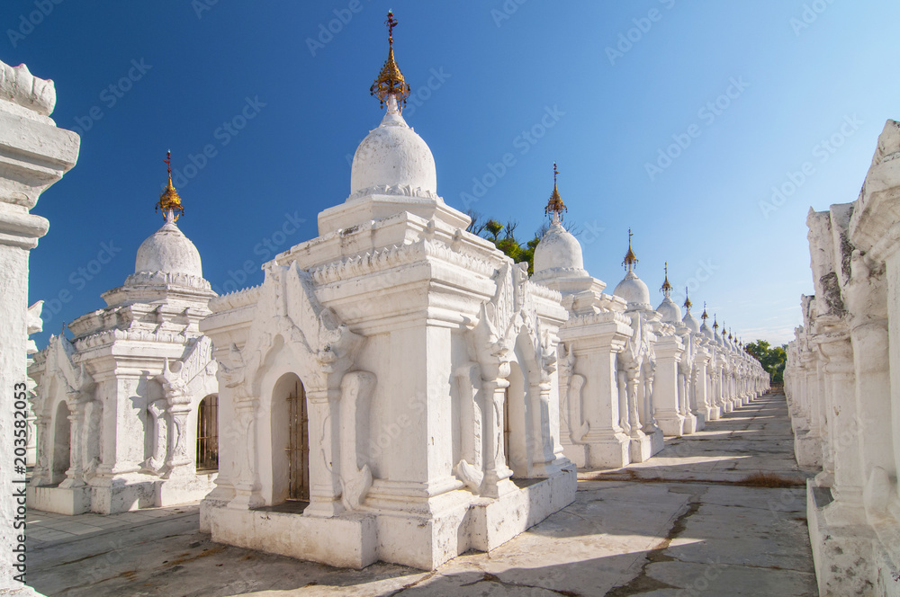Kuthodaw Pagoda contains the worlds biggest book. There are 729 white stupas with caves with a marble slab inside   page with buddhist inscription. Mandalay, Myanmar.