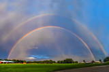 A double rainbow forms briefly, as the sun sets before a storm.