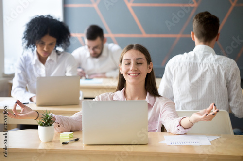 Calm smiling woman practicing office meditation in coworking space taking break for relaxation  mindful happy millennial student or employee feeling zen enjoying no stress free relief at work concept