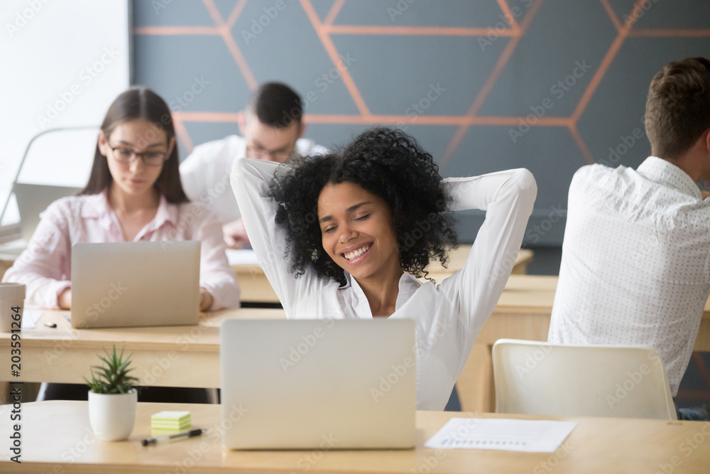 Smiling relaxed african american woman resting after computer work in office hands behind head, happy black employee student enjoying break stretching feeling no stress free relaxing in coworking Stock Photo | Adobe