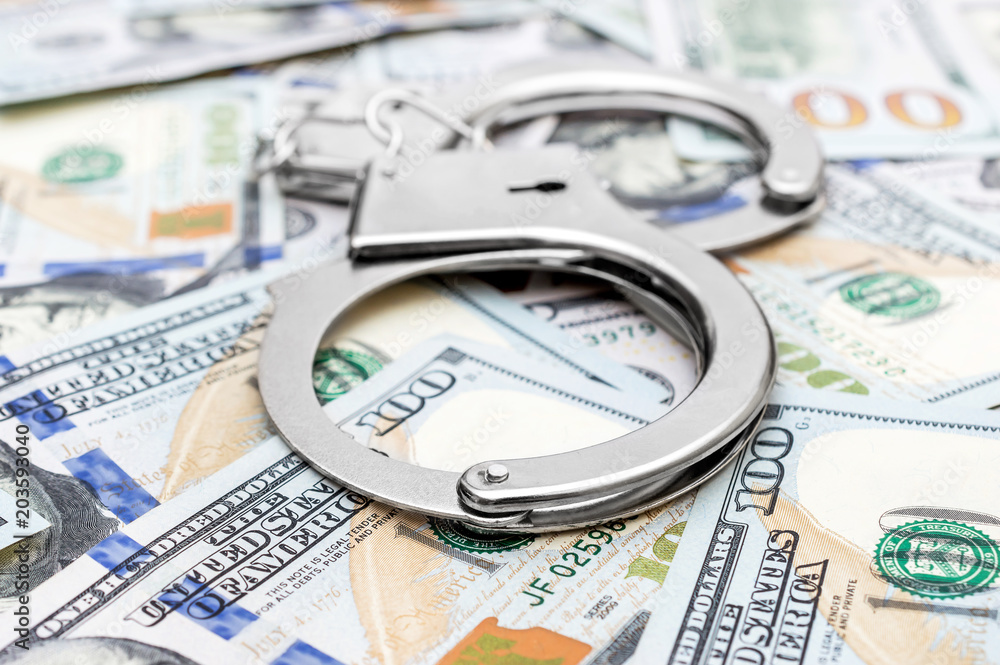 Handcuffs on the background of dollar bills. Handcuffs on the background of dollar bills.