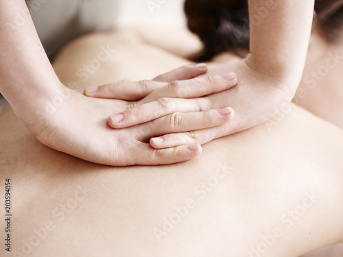 hands of masseuse performing massage on young asian woman