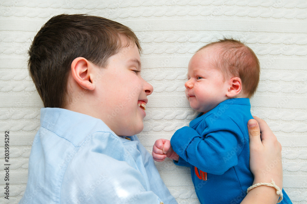 Big brother hugging his newborn baby girl. Toddler kid meeting new sibling Big brother hugging his newborn baby girl. Toddler kid meeting new sibling