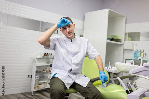 Male dentist standing over medical office background. Healthcare, profession, stomatology and medicine concept