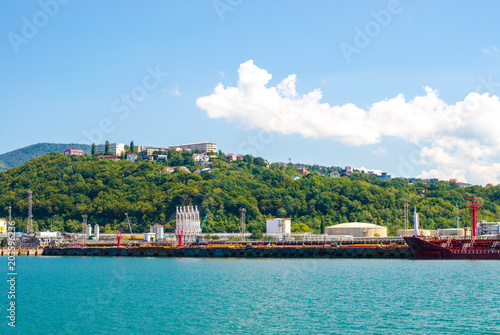 Shipyard on the coastline and town on the green hill on background