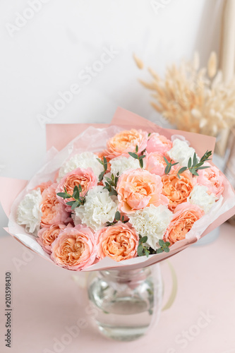 pastel orange and pink bouquet of beautiful flowers on wooden table. Floristry concept. Spring colors. the work of the florist at a flower shop. Vertical photo