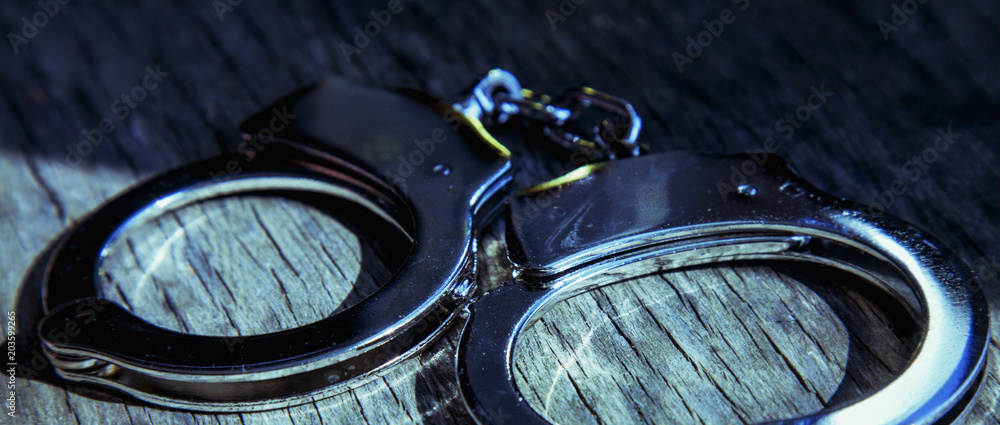 Criminal and  justice concept. Old handcuffs on wooden background.