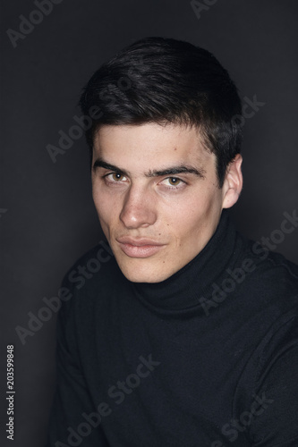 one young handsome man, model wearing turtleneck, simple studio upper body shot, black background. © HD92