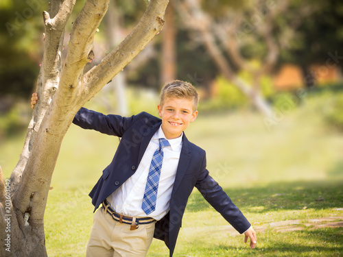fresh portrait of a boy dressed in a suit and tie in a park