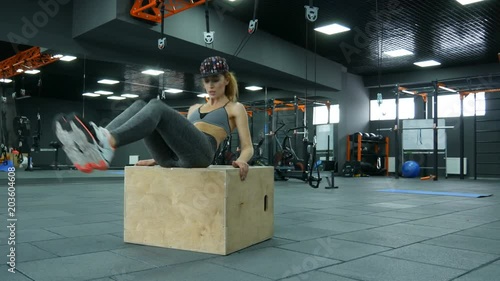 beautiful young woman swings the press at cube in fitness studio. sport and healthcare concept