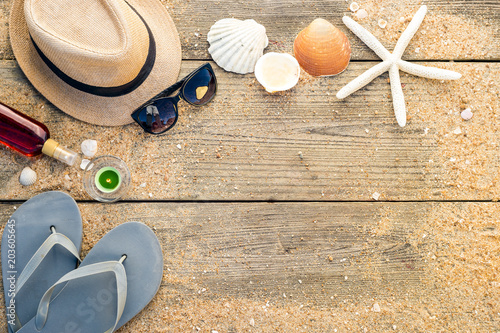 Summer hat, shells, sun glasses, tanning oil and flip flops with copy space