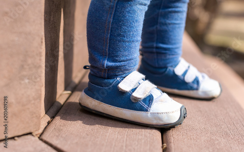 Toddler boy wearing his blue sneakers outside