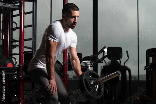 Muscular Man Exercising Back With Barbell