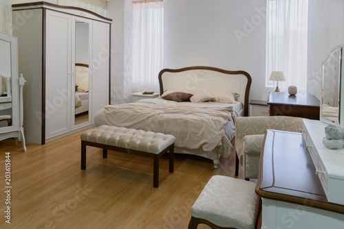 Light linen on bed in cozy bedroom with mirror
