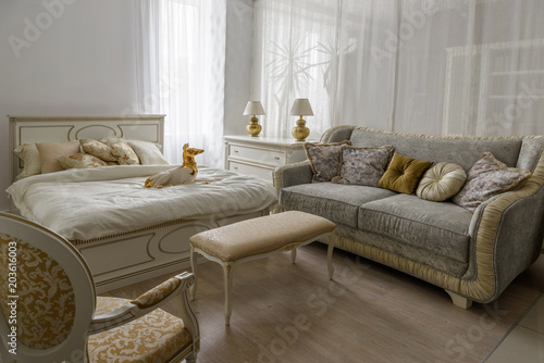 Dog statuette on bed with white linen in elegant room © LIGHTFIELD STUDIOS