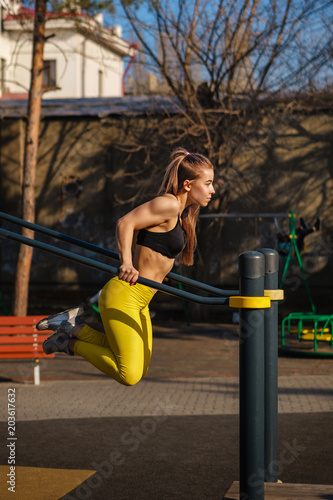 Girl on street workout. She pressed on parallel bar. She trains triceps.