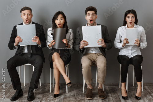shocked multicultural business people with folders and notebooks waiting for job interview