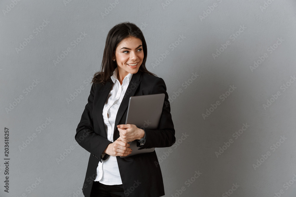 portrait of smiling businesswoman with laptop against grey wall background portrait of smiling businesswoman with laptop against grey wall background