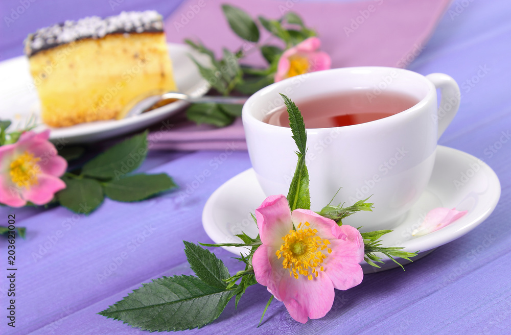 Cup of tea with cheesecake and wild rose flower on boards Cup of tea with cheesecake and wild rose flower on boards