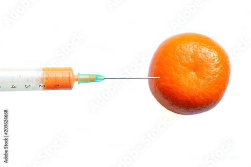 Injection of medical syringe with yellow liquid stuck in a fresh orange mandarin for growth. Isolated. White background 