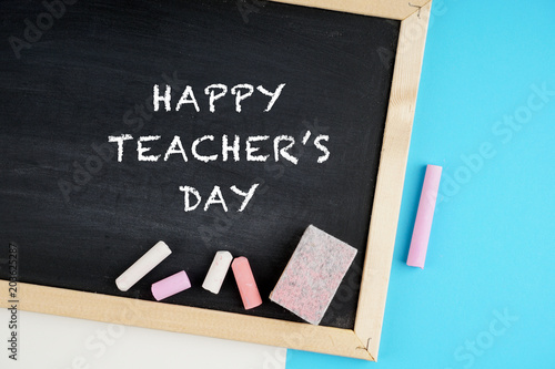Happy teacher's day concept with a black board, chalks, note book, pen 
