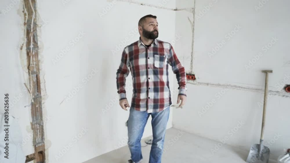 Young man looking around, checking wall at new home
Young man looking around, checking wall at new home