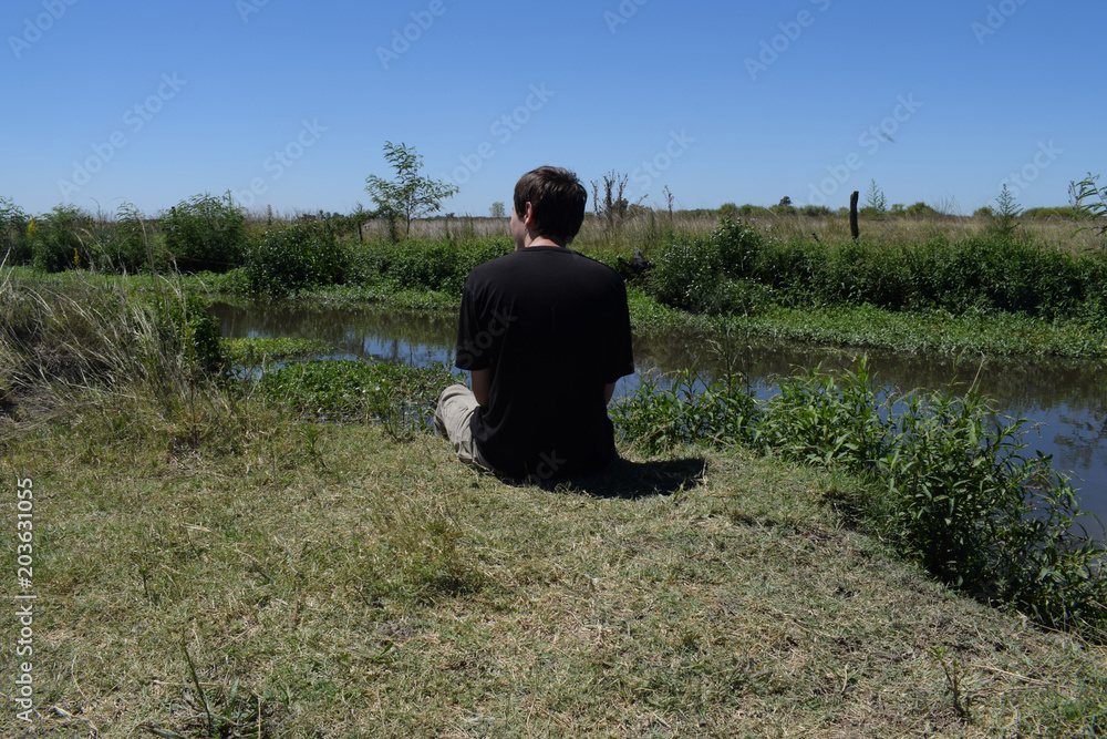 a young man on the shore of a wild river