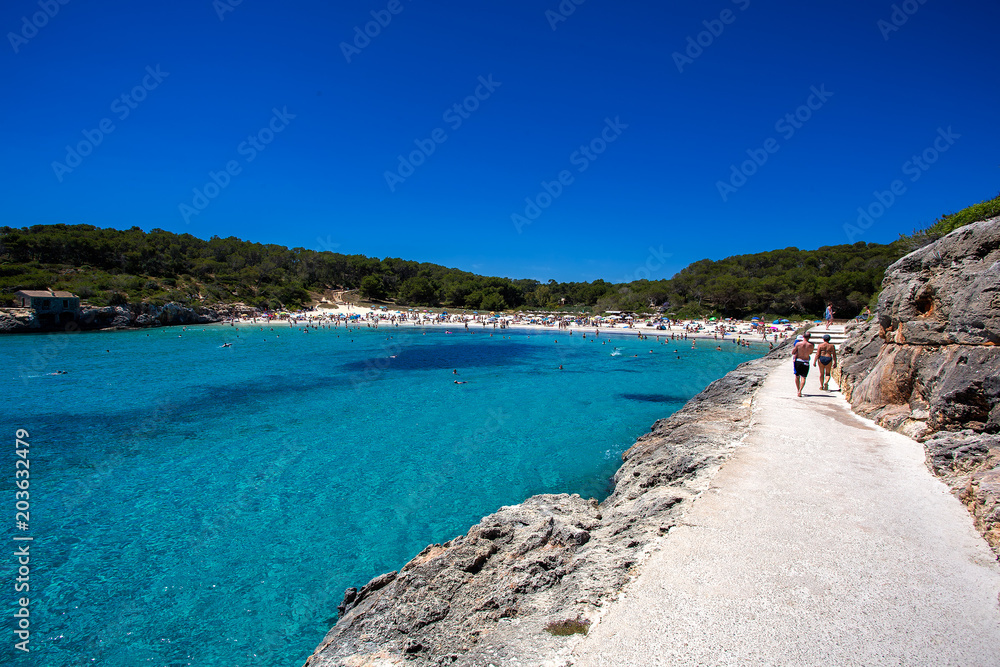 Beautiful crowded beach with turquoise water in summer season, Cala Modrago, Mallorca