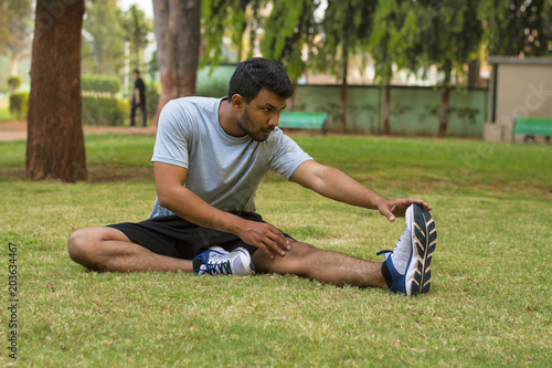 Young guy doing stretching exercise in a park