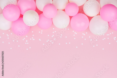 Pastel balloons and white confetti on pink background top view. Flat lay style.