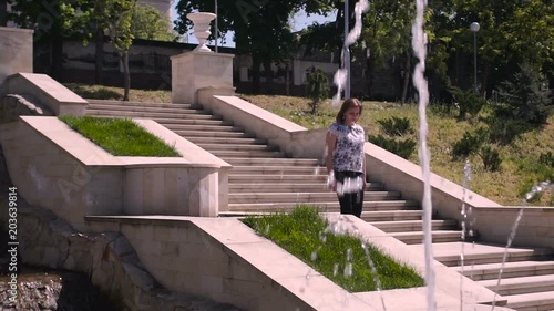 Young woman descends stone stairs in a sity parck photo