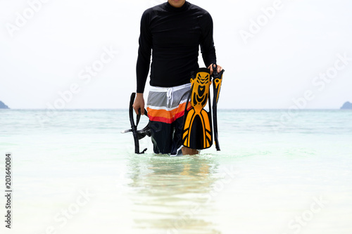 Man holding snorkeling gear come out from the sea in tropical island