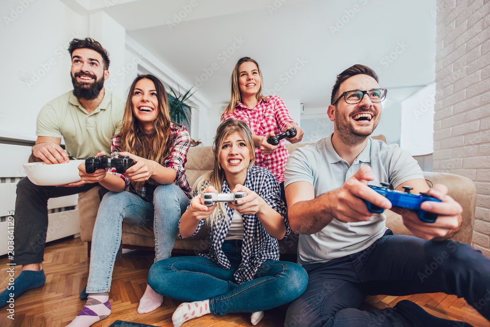 Playful friends playing video games online and having fun Stock