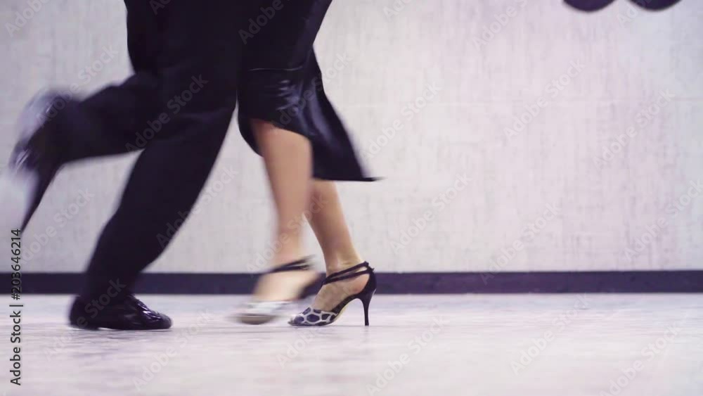 Legs of professional dancing couple in black suits dancing tango in the ballroom. Legs of professional dancing couple in black suits dancing tango in the ballroom.