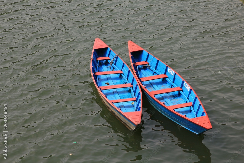 Blue red timber rowing boats on Fewa lake, Pokhara.