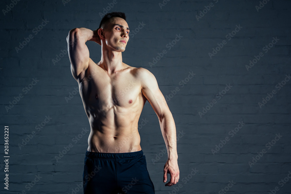 sexy naked man without clothes demonstrates the abs muscles on a dark background