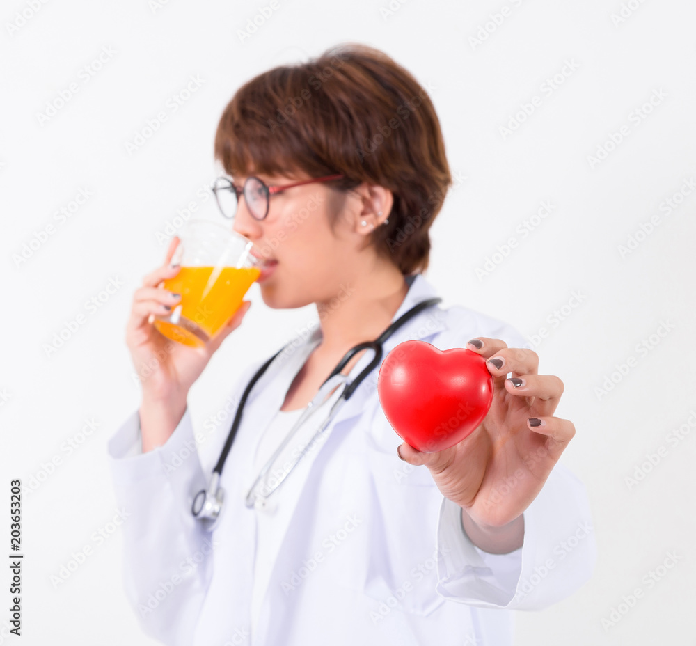 Happy woman doctor holding the red heart and orange juice. Isolated on white background. Studio lighting. Concept for healthy and medical Happy woman doctor holding the red heart and orange juice. Isolated on white background. Studio lighting. Concept for healthy and medical