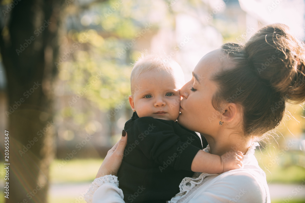 Mother kiss little son with love. Woman with child. Mom and baby boy outdoor. Mothers day concept. Happy family enjoy sunny day. Love care and trust Mother kiss little son with love. Woman with child. Mom and baby boy outdoor. Mothers day concept. Happy family enjoy sunny day. Love care and trust