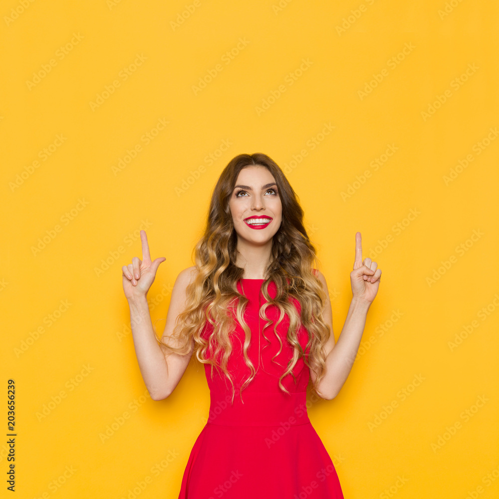 Young Woman In Red Dress Is Smiling, Pointing And Looking Up. Young Woman In Red Dress Is Smiling, Pointing And Looking Up.