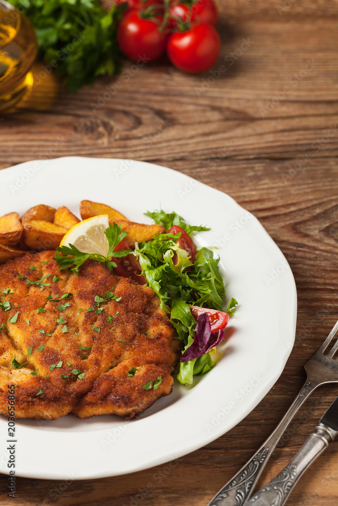 Chicken schnitzel, served with roasted potatoes and salad. Chicken schnitzel, served with roasted potatoes and salad.