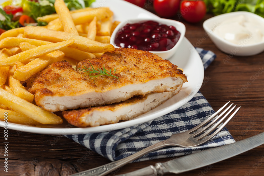 Chicken schnitzel, served with fries and salad. Chicken schnitzel, served with fries and salad.