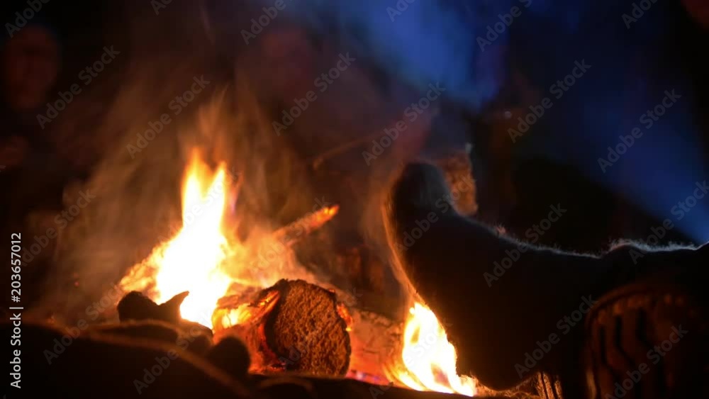 Male leg warming by the campfire into the night forest Male leg warming by the campfire into the night forest