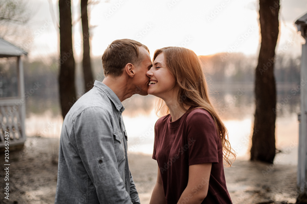 Naklejka premium Couple in love standing face to face and laughing on the background of lake
