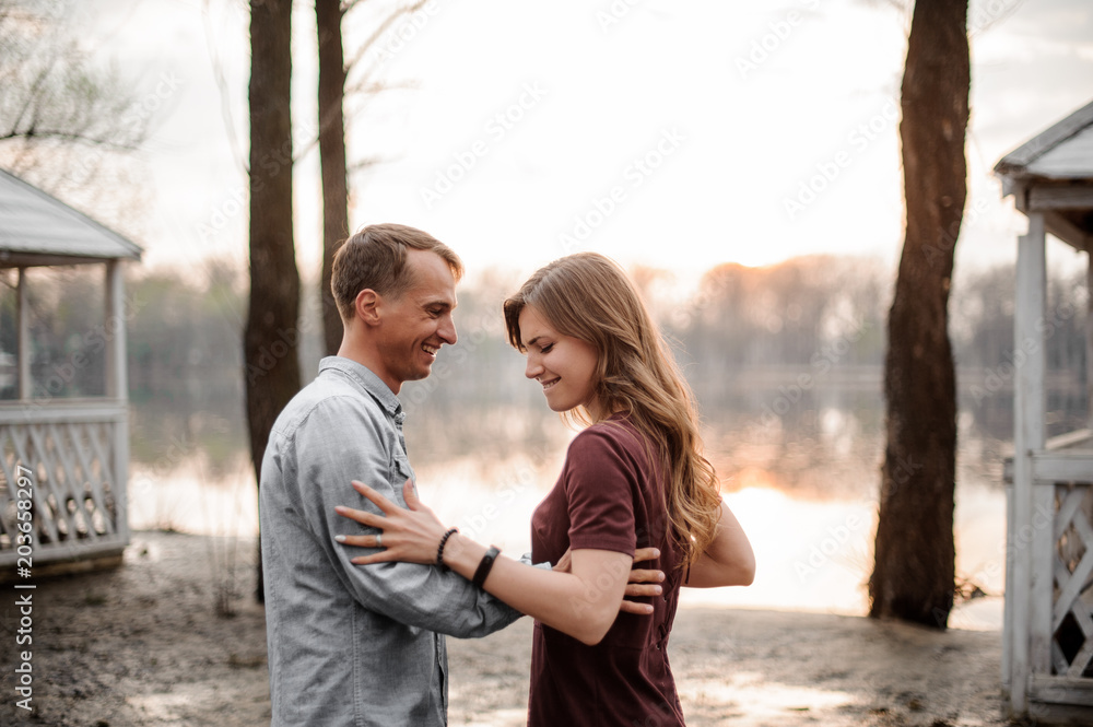 Couple in love standing on the background of sunset on a lake Couple in love standing on the background of sunset on a lake