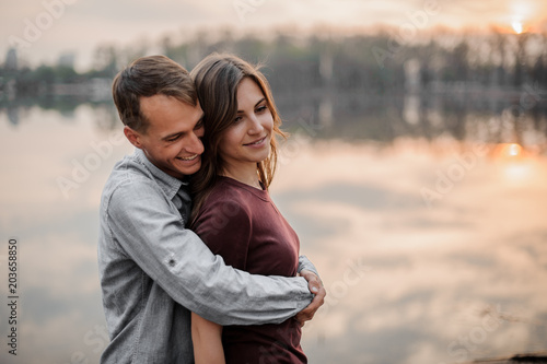 Man hugging from behind his woman on the background of lake