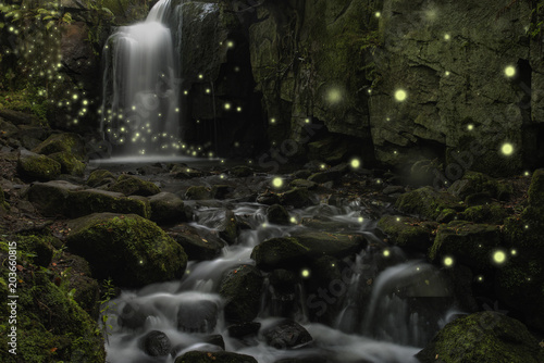 Beautiful fantasy image of fireflies over stream in rocky canyon landscape at dusk