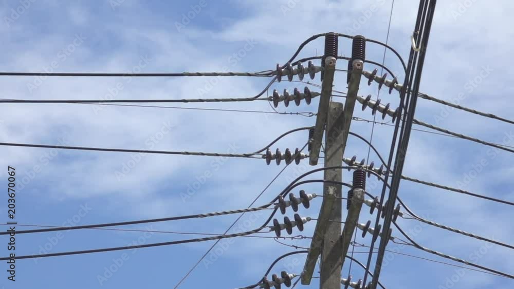 CLOSE UP: Concrete electricity pole towers into the bright blue summer sky. Tall telegraph post providing electricity to nearby towns in Thailand. Dangerous power cables running above a sunny street. CLOSE UP: Concrete electricity pole towers into the bright blue summer sky. Tall telegraph post providing electricity to nearby towns in Thailand. Dangerous power cables running above a sunny street.